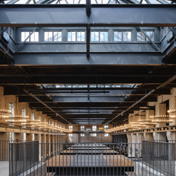 Artistic image of the Waterworks food hall from the upper level, with beams and glass ceiling visible.