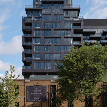 Vertical external shot of the residential portion of the building with the dog park next to the building in the foreground.