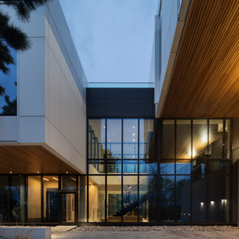 Night shot of the external building with windows and exposed wood features.