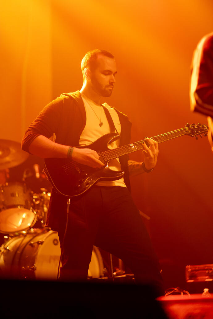 A band member playing the electric guitar.